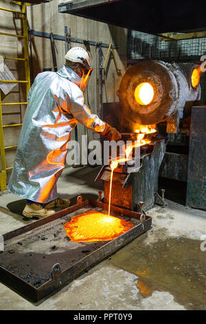 Lavoratore in abbigliamento protettivo versando in oro dal forno ad una miniera d'Oro in Australia Occidentale Foto Stock