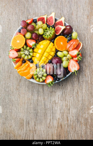 Un assortimento di frutti e bacche platter, fragole mirtilli, mango orange, Apple, uva da tavola, kiwi sul legno grigio Sfondo, copiare lo spazio per testo, ve Foto Stock