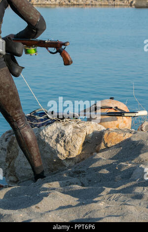 Vista del raccolto di scuba diver uomo adulto su un litorale con la pesca subacquea ingranaggio (alette, fucile), spazio per il testo Foto Stock