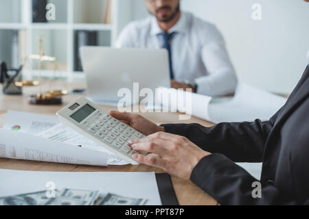 Immagine ritagliata di finanziatori utilizzando la calcolatrice e il computer portatile in ufficio Foto Stock