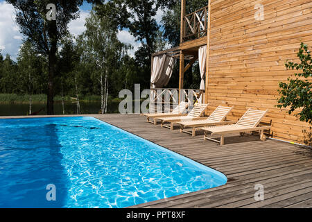 Vuoto accogliente chaise lounge vicino alla piscina a giornata di sole Foto Stock