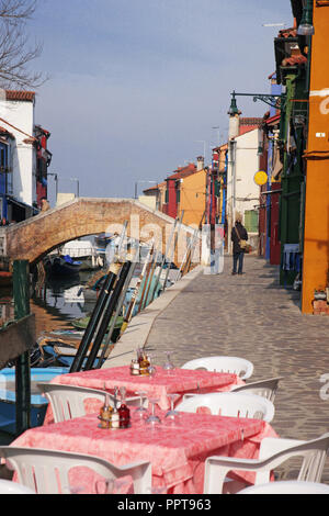 Rio Terranova, Burano, Venezia, Italia: canal, ponte tavole di ristorante, case vivacemente colorate e molte barche ormeggiate Foto Stock