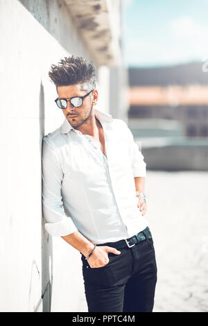 Ritratto di successo di un giovane imprenditore vestito appoggiata alla parete . Concetto di Moda Giovane Foto Stock
