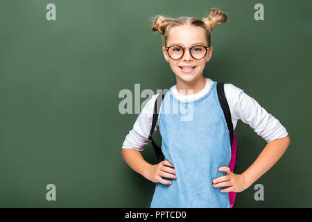 Schoolchild sorridente in bicchieri in posa in prossimità di Blackboard Foto Stock