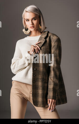 Donna elegante che pongono in bianco maglione e autunno giacca di tweed, su grigio Foto Stock