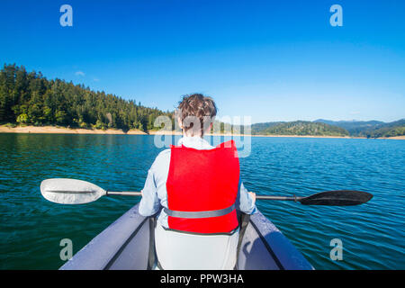 Giovane donna seduta in kayak e di prendere un periodo di riposo sul lago Lokvarsko nella regione di Gorski Kotar, Croazia. Ragazza attivo avente godendo di esperienza avventurosa Foto Stock