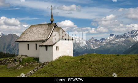 Nei pressi del villaggio di Bettmeralp nel cantone del Vallese (Svizzera) una piccola chiesa bianca è in piedi in campi verdi Foto Stock