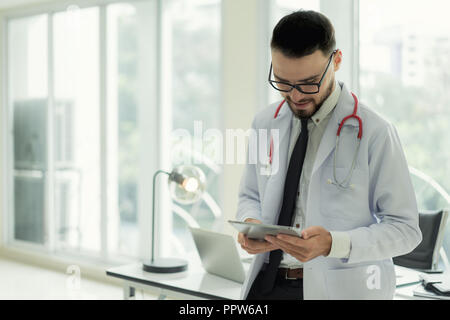 Medico in ospedale lavora con la tecnologia moderna per un sano. Gentile Dottore uomo cercando e sorriso per il buon risultato di dati paziente grafico. Foto Stock