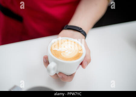 Barista detiene una tazza con un caffè figurativo latte sotto forma di un Apple Foto Stock