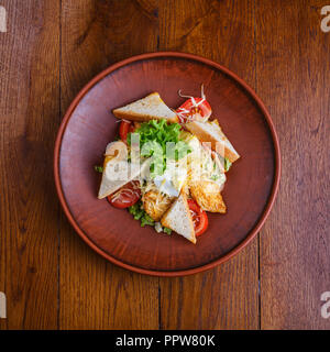 Il piatto con il pollo, pomodori, crostini, insalata, uova e formaggio. Un pasto in un pub Foto Stock