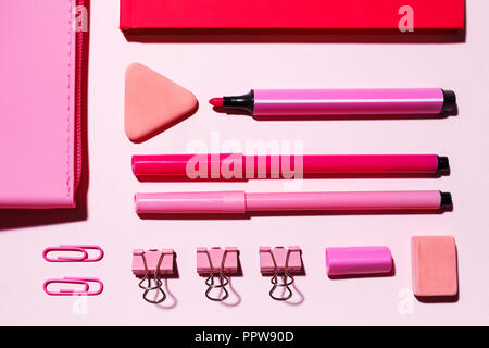 Gli articoli di cancelleria sono geometricamente disposti sulla tavola. Articoli di cancelleria in toni di colore rosa. Appartamento laico, vista dall'alto. Foto Stock