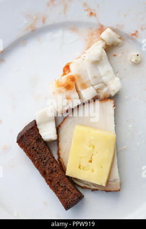 Resti di cibo dopo una gustosa cena - grasso con pane e formaggio su una piastra sporca. Vista dall'alto di ripresa macro Foto Stock