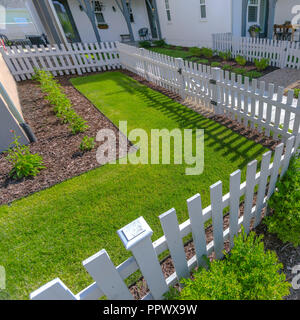 Recinzione bianco intorno a un soleggiato cortile paesaggistico Foto Stock