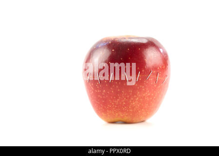 Due metà di una mela rossa tenuti insieme mediante punti metallici isolati su sfondo bianco. Foto Stock