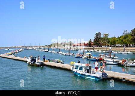 Vista delle barche e yacht ormeggiati nel porto turistico con il suo lungomare (Avenida 5 de Outubro) e il mercato coperto degli edifici per il lato destro, Olhau, ALG Foto Stock