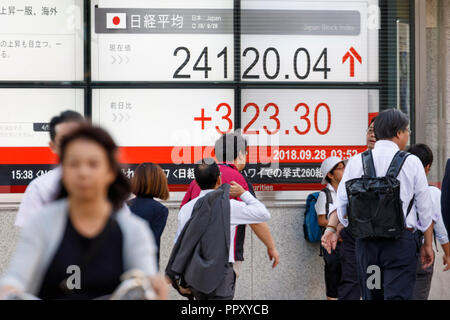 Tokyo, Giappone. Il 28 settembre 2018. I pedoni a piedi passato un magazzino elettronico di bordo che mostra in Giappone il Nikkei stock medio su Settembre 28, 2018, Tokyo, Giappone, il Nikkei Stock finito medio a 24,120.04, fino 323.30 o 1,36 percento, il suo più alto vicino a quasi 25 anni dal gennaio 1991. Credito: Rodrigo Reyes Marin/AFLO/Alamy Live News Foto Stock