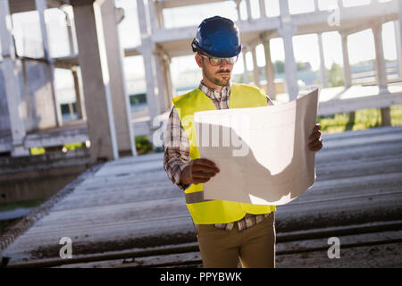 Ingegnere di lavoro sul sito in costruzione e blueprint di contenimento Foto Stock