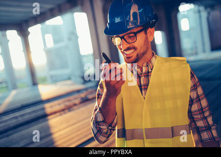 Architetto maschio comunicando su un walkie-talkie presso il sito Foto Stock