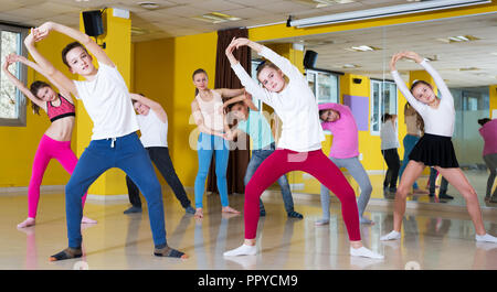 Il gruppo di formazione tweens movimenti di danza moderna in coreografia di classe con donna coach Foto Stock