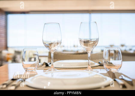 Tavolo con piatti e bicchieri e posate pronto per il pranzo in un ristorante elegante Foto Stock