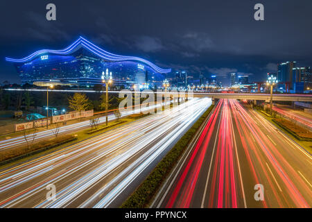 Chengdu, nella provincia di Sichuan, in Cina - Settembre 27, 2018: semaforo sentieri sul Tianfu avenue di notte illuminata con il nuovo secolo centro globale in background Foto Stock