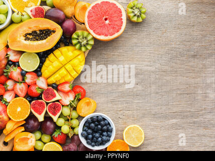 Vista superiore di sani frutti, fragole mirtilli, mango orange, pompelmo, banana papaya apple, uva da tavola, kiwi, fichi sul legno grigio Sfondo, Foto Stock