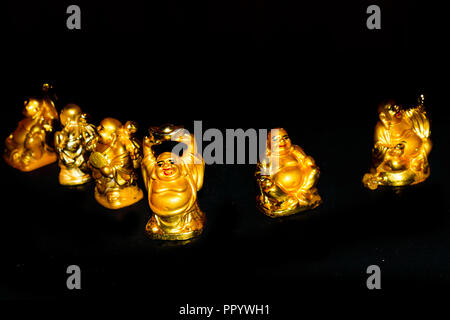 Un Golden ridere Buddha con mentalità rilassato. Isolato in uno sfondo scuro. Messa a fuoco selettiva e profondità di campo Foto Stock