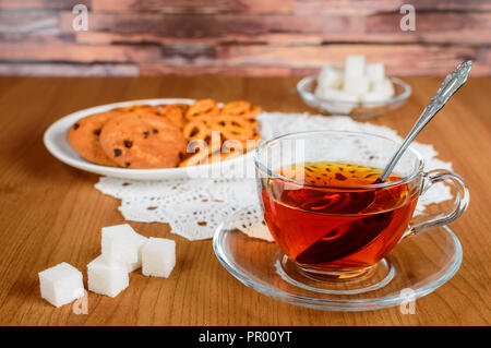 Ricco il tè in un bicchiere di vetro. i cookie e lo zucchero raffinato Foto Stock