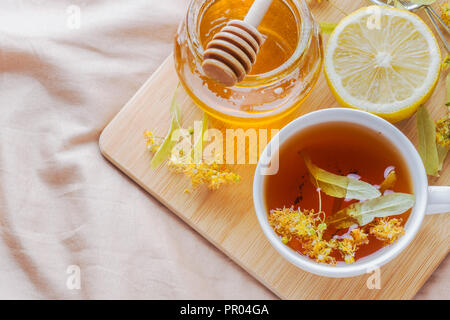 Tè con Linden, miele e limone. Il vassoio sul letto, il concetto di trattamento di raffreddori Foto Stock