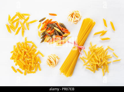 Un assortimento di pasta cruda laici piatta sul bianco. spaghetti fusilli penne tagliatelle girandole Foto Stock