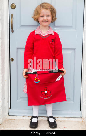 Quattro anni di schoolgirl / School girl / bambino / kid nella nuova uniforme al suo sportello anteriore, di uscire di casa per la scuola sul suo primo / primo giorno di scuola. Regno Unito. Foto Stock