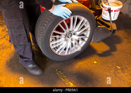 Pneumatico montatore/meccanico rimuovere / rimozione / elimina / rimozione di un vecchio pneumatico Michelin da un auto / automobili cerchione. Regno Unito. (102) Foto Stock