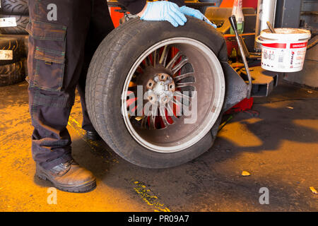 Pneumatico montatore/meccanico rimuovere / rimozione / elimina / rimozione di un vecchio pneumatico Michelin da un auto / automobili cerchione. Regno Unito. (102) Foto Stock