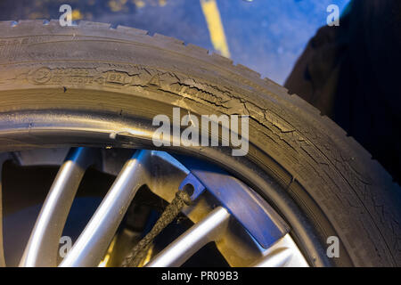 Pneumatico montatore/meccanico rimuovere / rimozione / elimina / rimozione del vecchio rotto pneumatico con il crack / crepe sulla parete laterale fianco & car / auto cerchio. Regno Unito Foto Stock