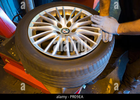 Pneumatico montatore/meccanico rimuovere / rimozione / elimina / rimozione di un vecchio pneumatico Michelin da un auto / automobili cerchione. Regno Unito. (102) Foto Stock