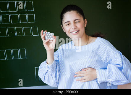 Sconvolto studente con piils tiene per mano di cuore nei pressi di Blackboard Foto Stock