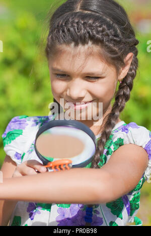 Sorpresa ragazza guarda beetle sulla vostra mano attraverso la lente di ingrandimento Foto Stock