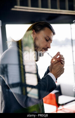 Vista laterale al giovane imprenditore godendo il suo sigaro in pausa Foto Stock