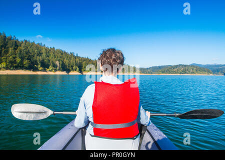 Giovane donna seduta in kayak e di prendere un periodo di riposo sul lago Lokvarsko nella regione di Gorski Kotar, Croazia. Ragazza attivo avente godendo di esperienza avventurosa Foto Stock