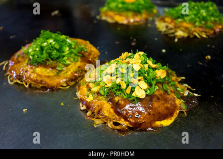 Okonomiyaki, in stile Giapponese gustosi pancake, su una grande piastra in un ristorante, Hiroshima, Giappone, Asia Foto Stock