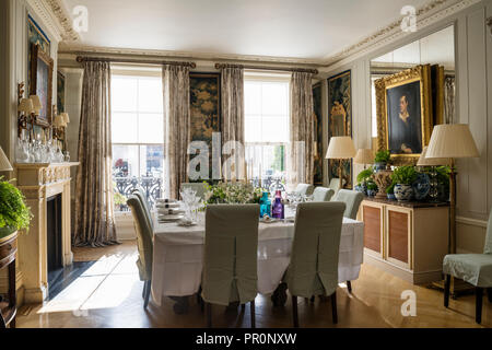 Square tavolo da pranzo con grandi finestre a ghigliottina di slittamento e sedie con ottocento verdure arazzo pannelli Foto Stock