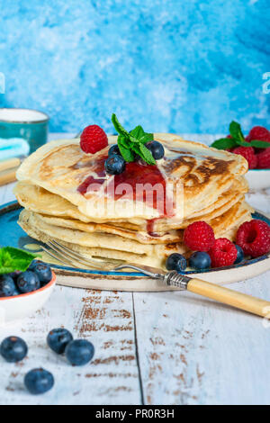 Una pila di pancake con frutta fresca, marmellata e crema su una piastra Foto Stock