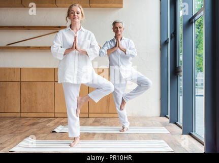 Coppia senior di eseguire la posizione dell'albero su Materassini da yoga Foto Stock