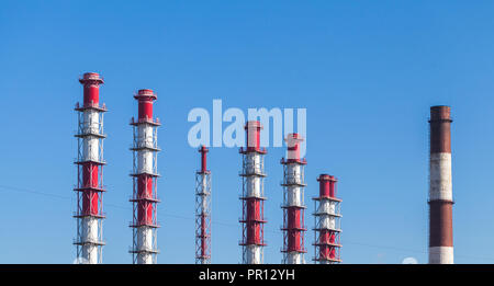 Rigato bianco rosso camini industriali oltre il cielo blu Foto Stock