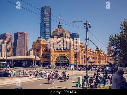 Persone stanno attraversando la strada di fronte alla stazione di Flinders Street nel CBD di Melbourne, Australia. È chiaro cielo. Foto Stock