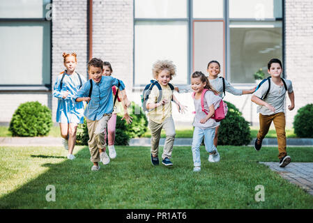 Gruppo di allievi adorabili che corrono dal giardino della scuola Foto Stock