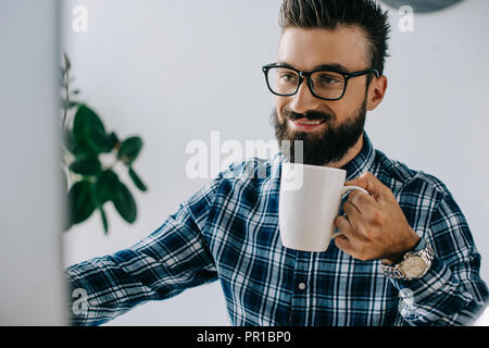 Ritagliato shot di felice giovani seo con tazza di caffè a lavorare con il computer in ufficio Foto Stock
