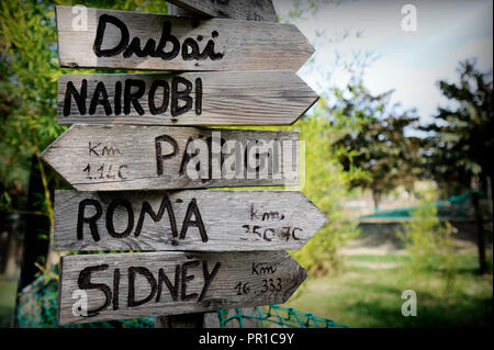 Via segni nel parco naturale che indica le direzioni per diversi luoghi del mondo. Piante verdi sullo sfondo. Presi nel nord Italia. Foto Stock