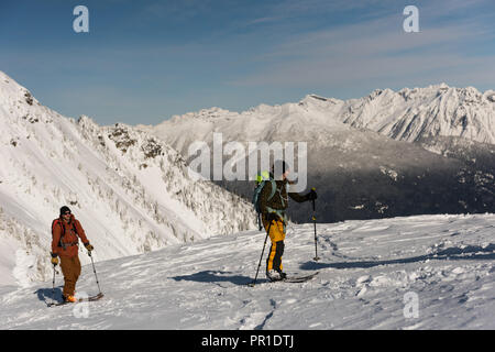 Gli sciatori a camminare su una montagna innevata Foto Stock