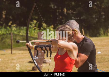 Il trainer di istruire la donna su tiro con l'arco Foto Stock